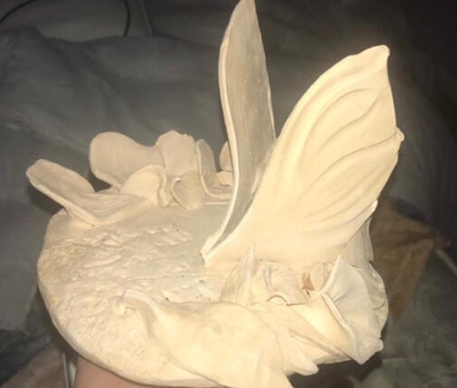 Done using clay and slip, texture on the part the butterfly is placed on was created using a rock. It was inspired by a dead butterfly in the art room. Not painted or glazed.